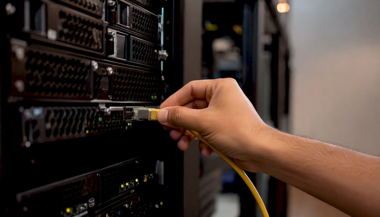 Hand connecting data cable in server rack