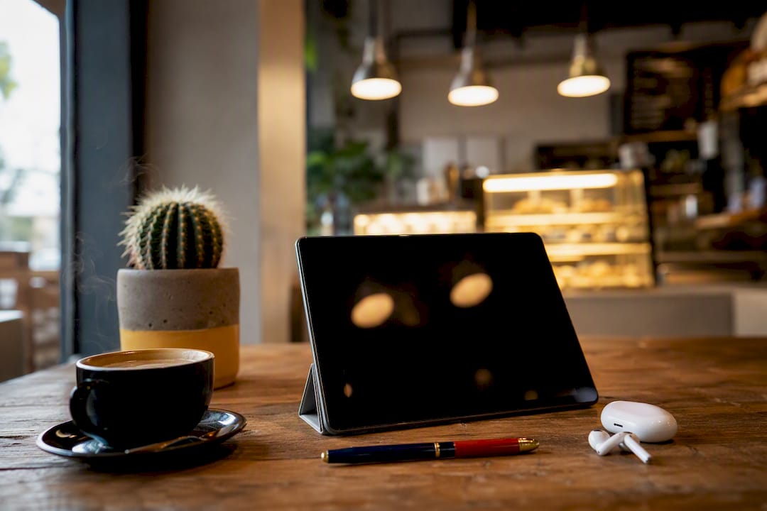 Tablet and coffee on wooden table in office