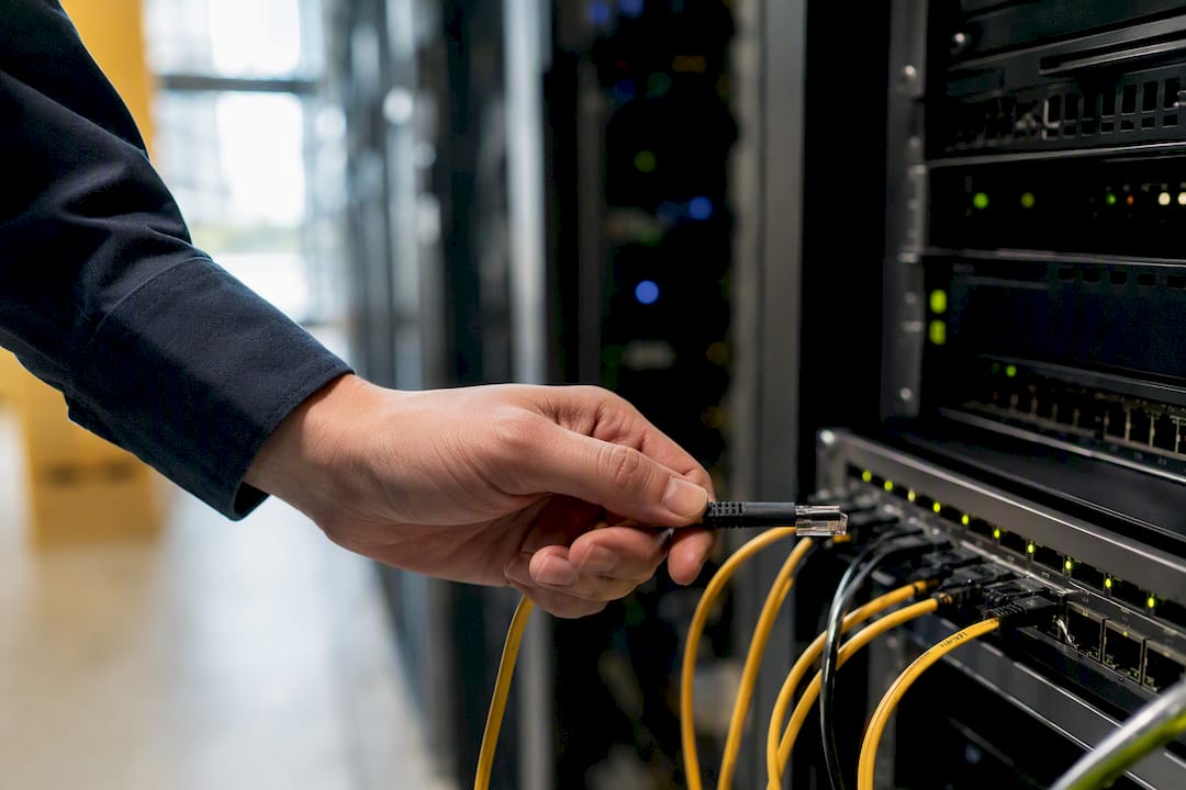 Hand holding cable connector in server room