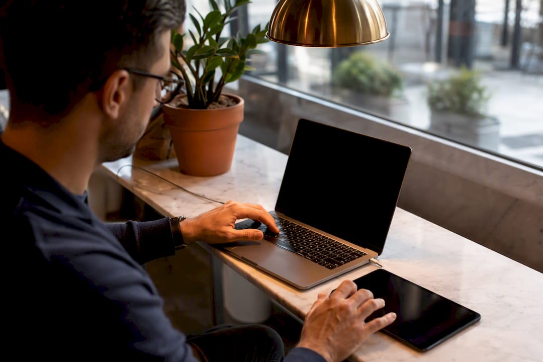 Hands at laptop and tablet in modern office